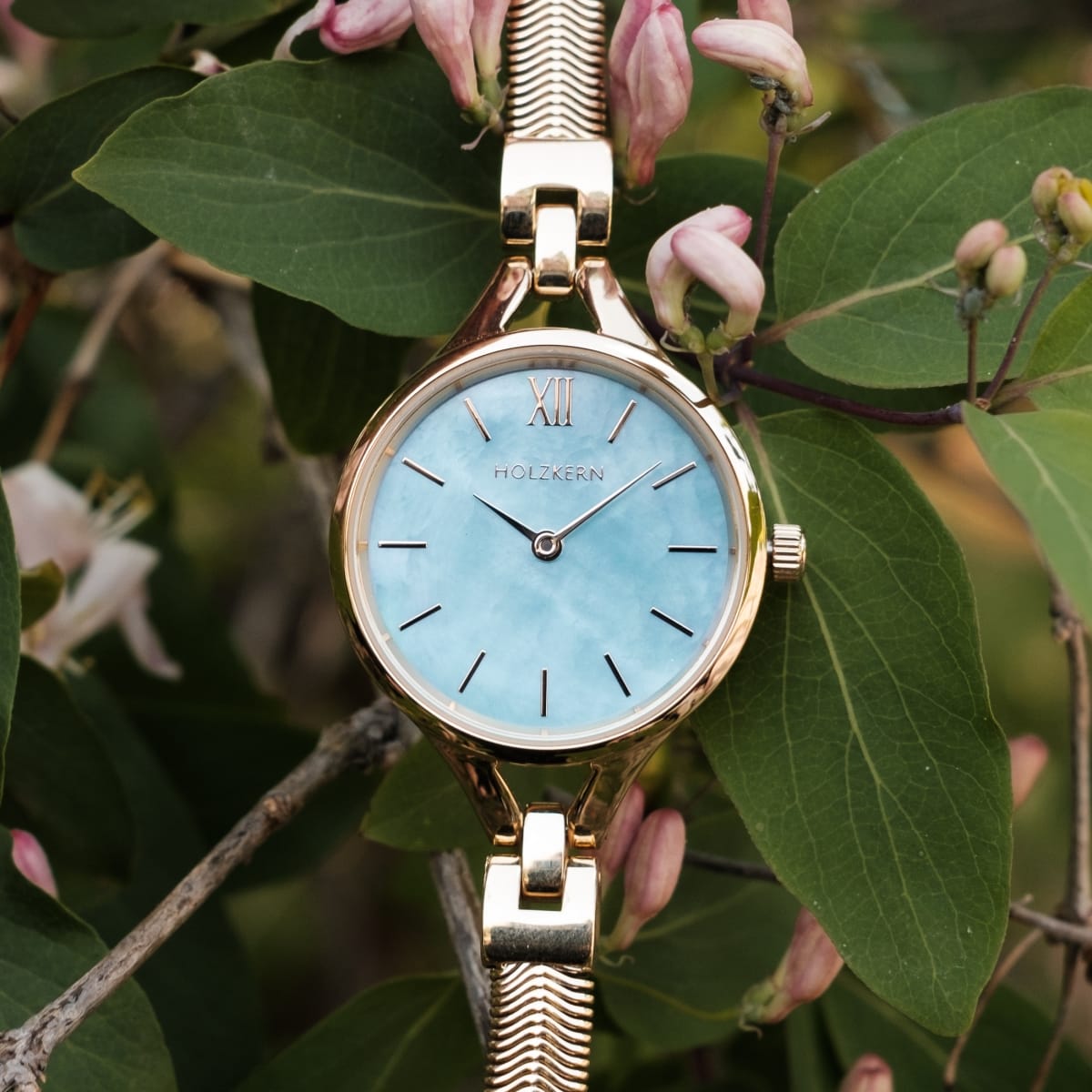 "Shesha" watch featuring a nacre face and gold accents in an elegant nature-inspired setting.