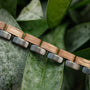 "Duet" bracelet featuring oak wood and gray metal in a natural setting with leaves.