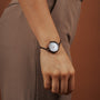 "Touching" watch featuring a nacre face and antique copper accents, elegantly styled on the wrist.