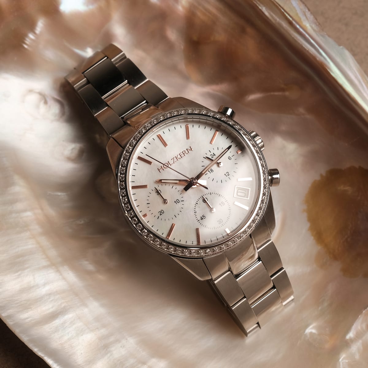 "The Balanced" watch, featuring a nacre dial and silver bracelet, offers a sleek and elegant look.