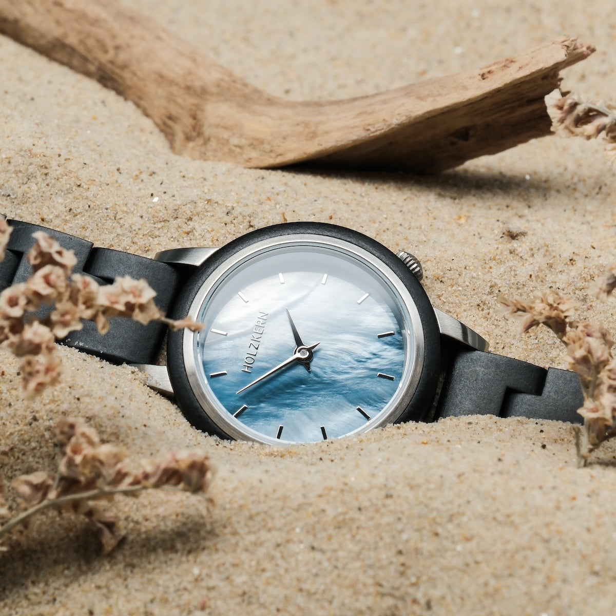 "Big Sur" watch, featuring a maple case and nacre dial, showcases a natural, elegant style nestled in sand.