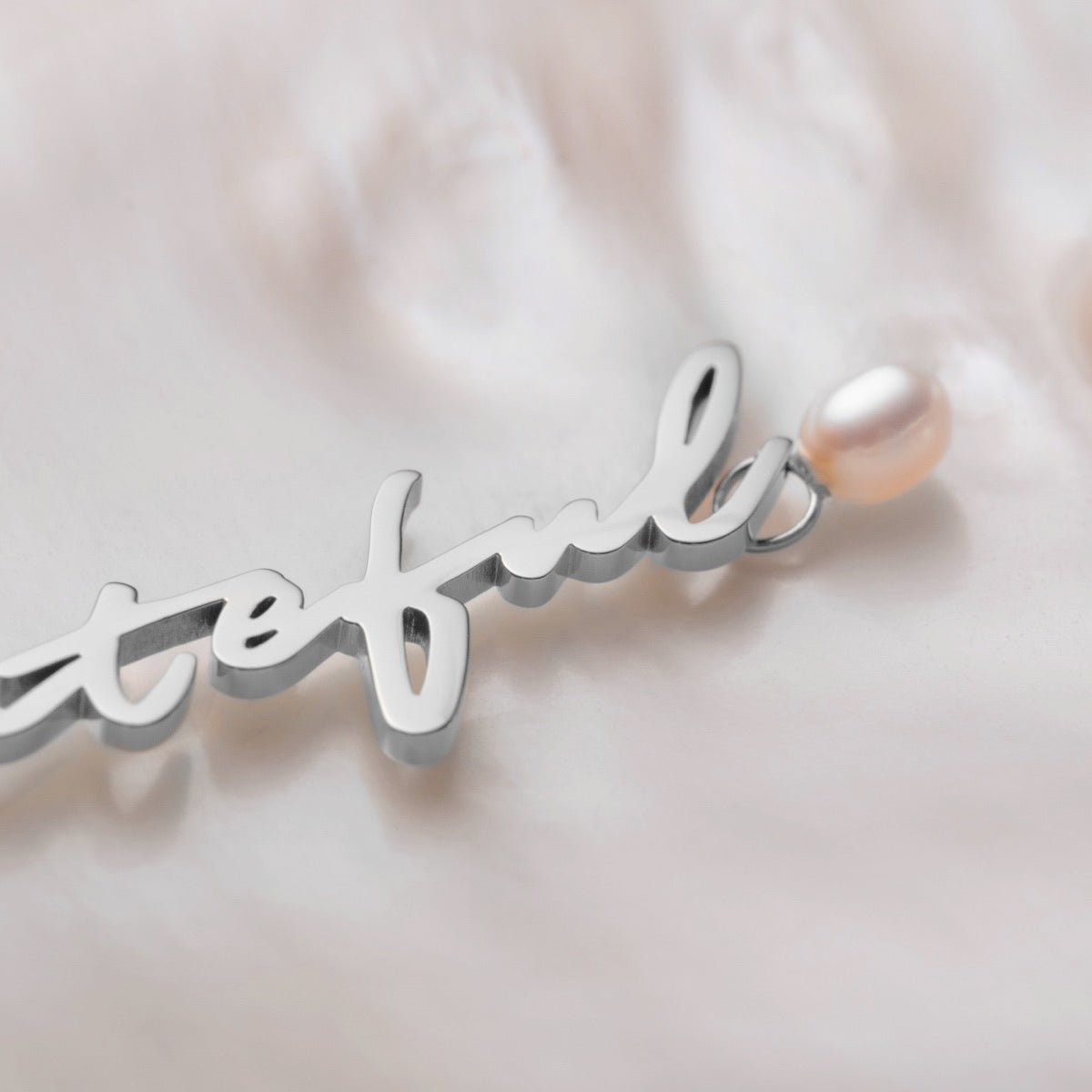 "Grateful-Charm" pendant in elegant silver script with a single pearl accent.