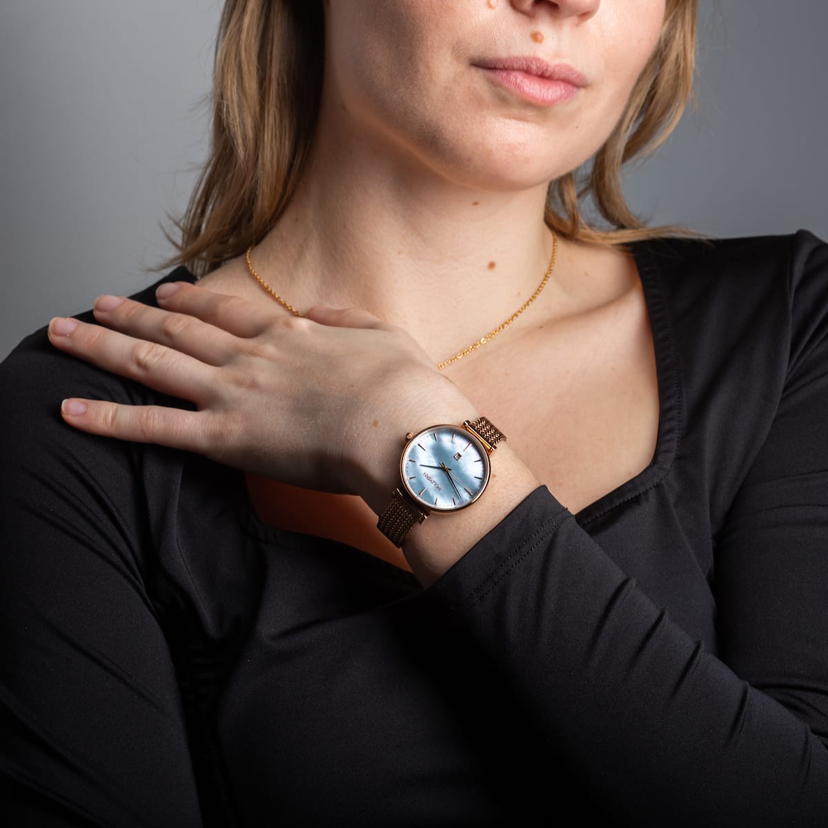 "Chitchat" wristwatch featuring a nacre dial and rose gold finish, worn on a woman's wrist in a stylish setting.