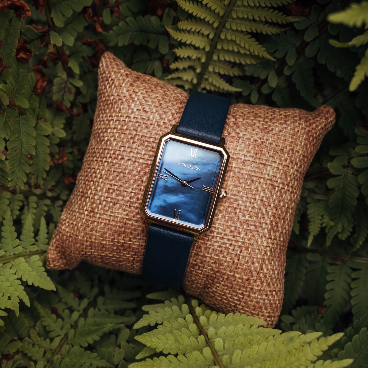 "Sapientia" watch featuring a nacre dial and rose gold accents, stylishly displayed on a cushion in a natural setting.