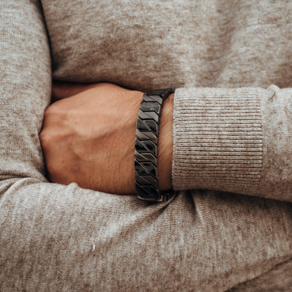 "Baritone", a stylish bracelet with a dark grey chain design, complements a cozy sweater aesthetic.