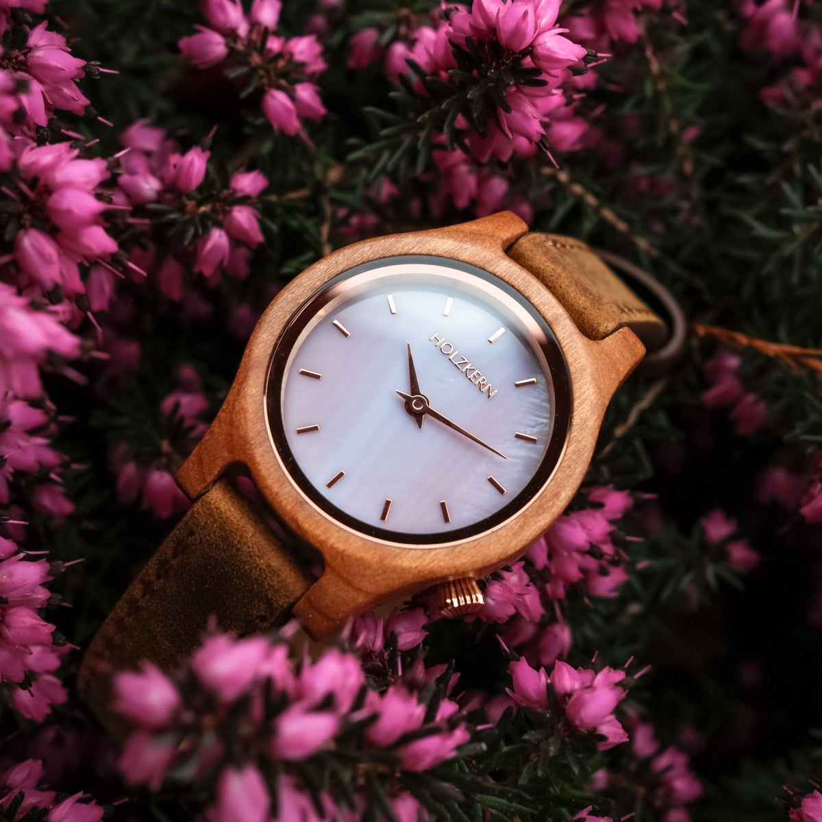 "Cinque Terre watch featuring a cherrywood case and mother-of-pearl dial, set against vibrant pink flowers."
