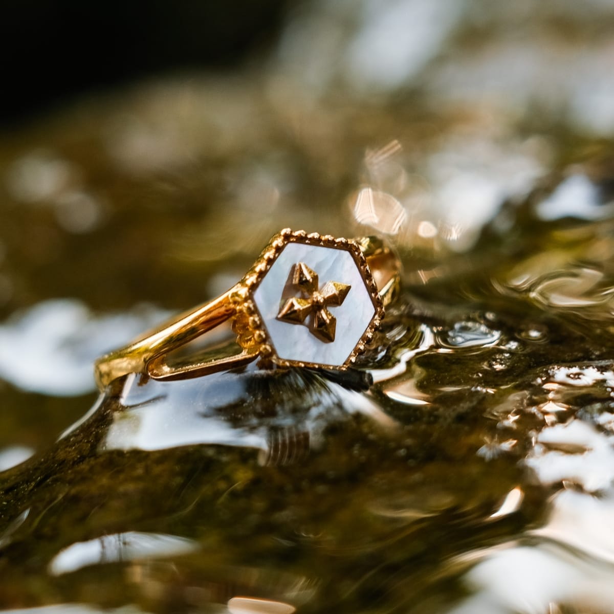 "Spectral Ring", a gold ring with white nacre accents, showcasing an elegant and intricate design.