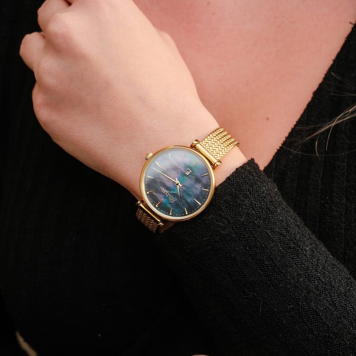 "Giggles", a stylish watch featuring a nacre dial and gold-tone mesh bracelet, worn on a wrist.