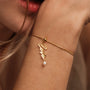"Love-Charm" bracelet featuring an elegant gold charm with a pearl accent, worn gracefully on the wrist.