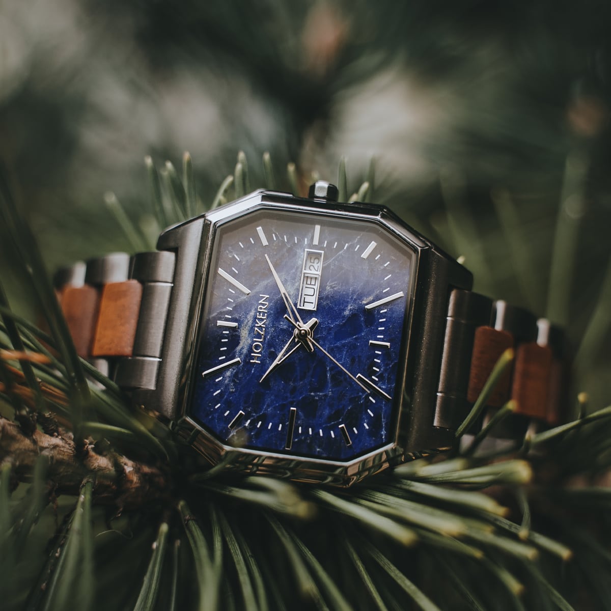 "Moneo" watch featuring koa and marble design with silver accents on a nature backdrop.