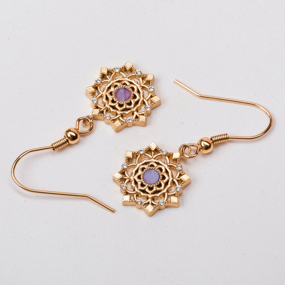 "Aphonia Earrings" are elegant gold earrings with intricate amethyst accents and a stylish design.