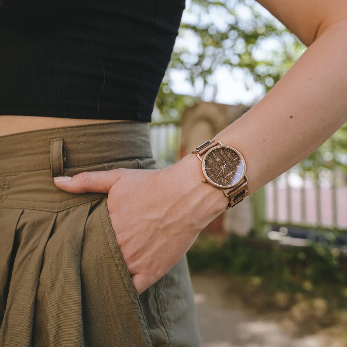 "Belvue" watch in Walnut wood, featuring a sleek, minimalist design worn by a person outdoors.