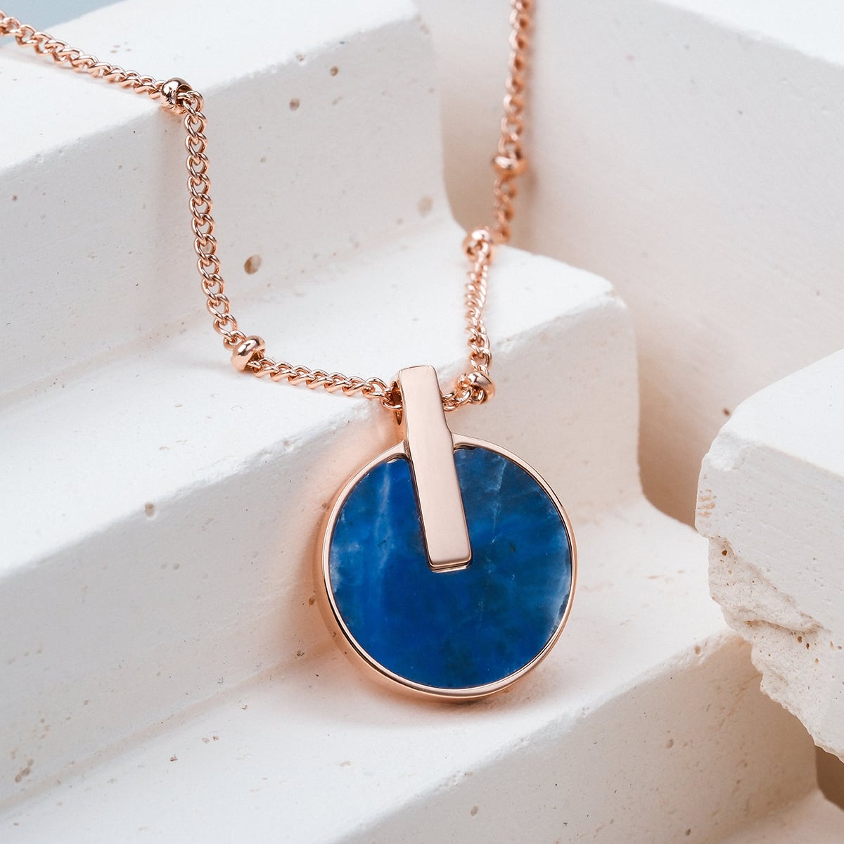 "Opacity Necklace" necklace featuring a round blue marble pendant with rose gold accents on a stylish chain.