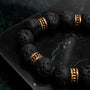 "Superset" bracelet featuring lava beads with gold accents on a dark marble background.