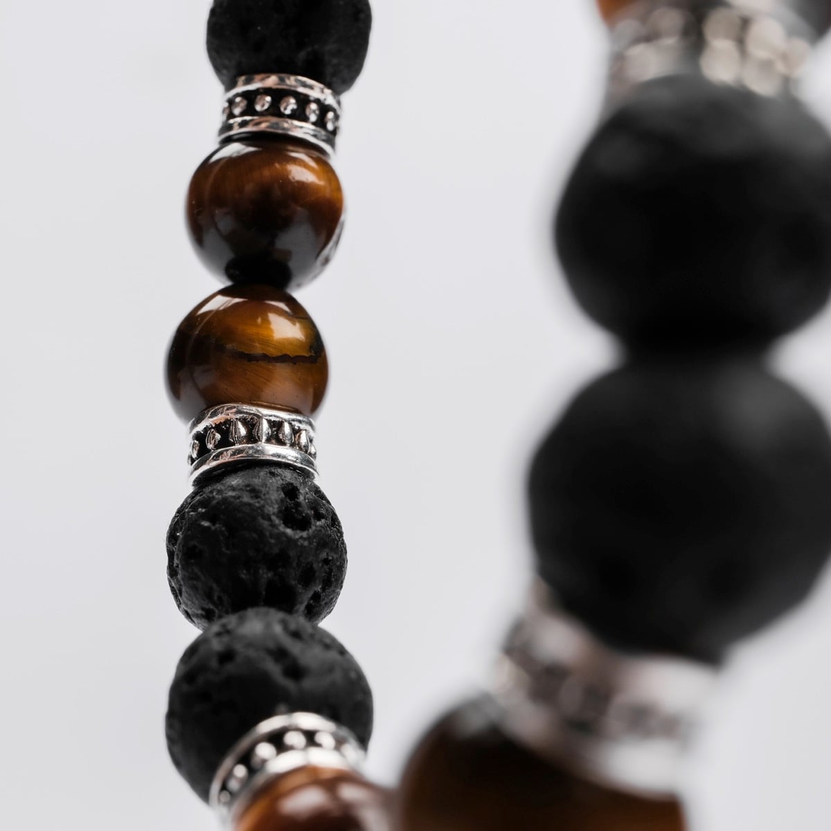 "Superset", a bracelet featuring tiger eye and lava stone beads with a stylish, earthy design.