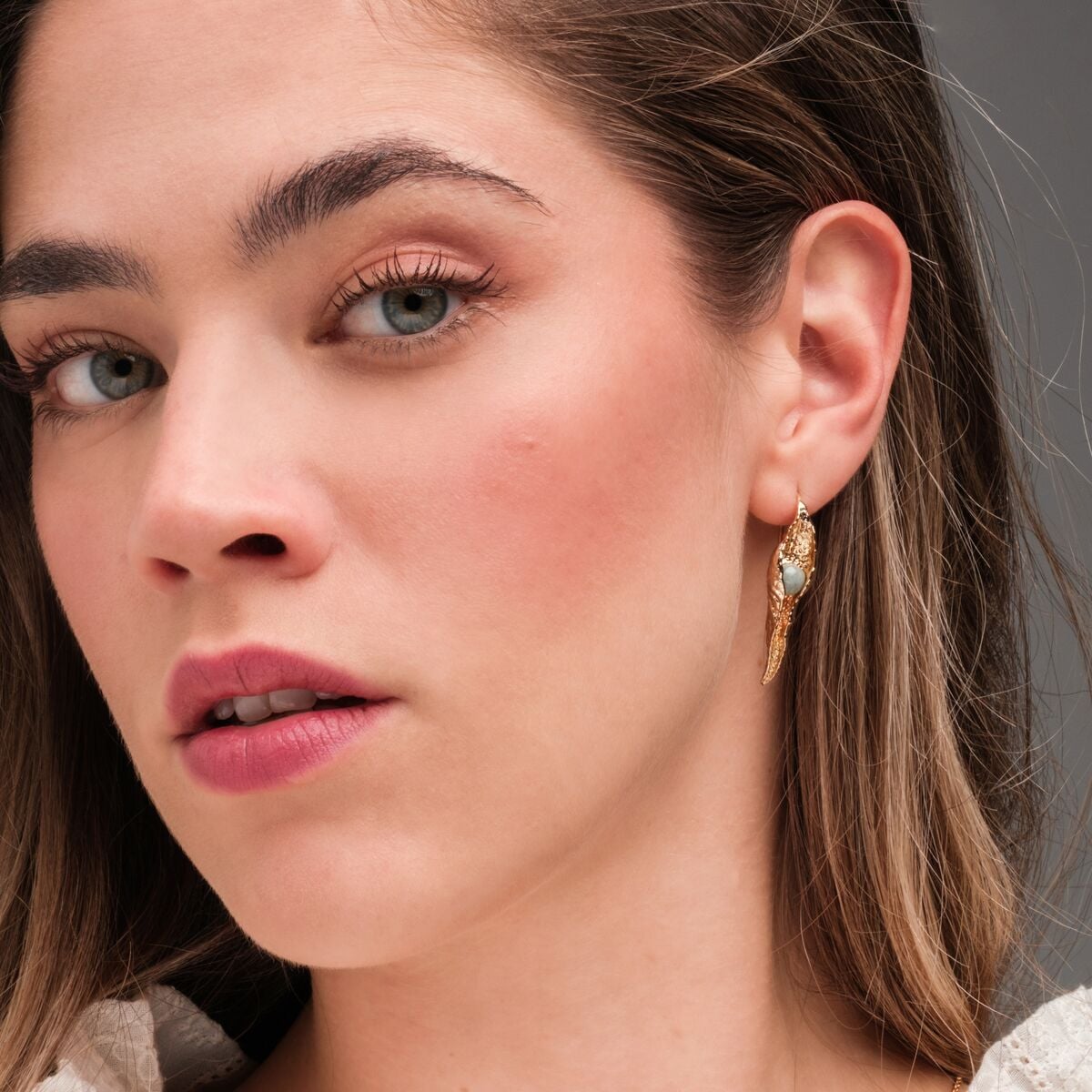 "Chalice earrings", elegant gold earrings with Amazonite accents, worn by a model.
