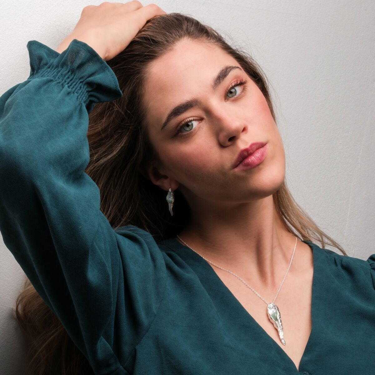"Chalice Necklace", a stylish necklace with an amazonite stone set in silver, elegantly worn by a model in a teal top.