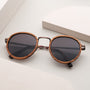 "The Loving" sunglasses feature a round zebrawood frame and antique copper accents for a stylish, modern look.