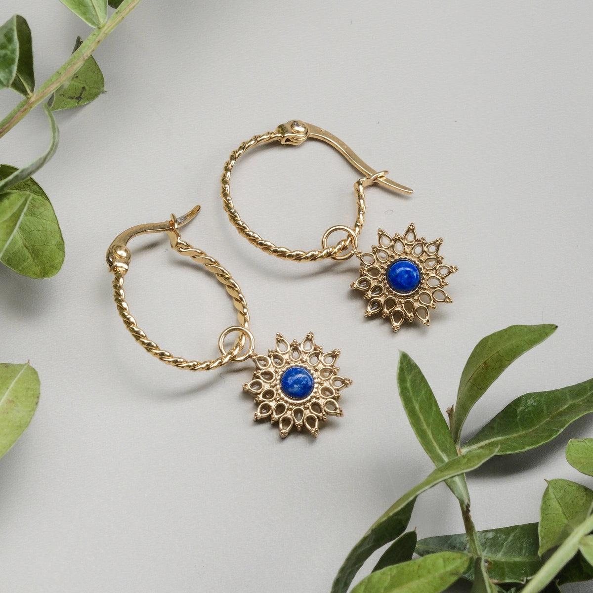 "Suncatcher Earrings", elegant earrings with gold detailing and lapis lazuli accents, featuring a sunburst design.