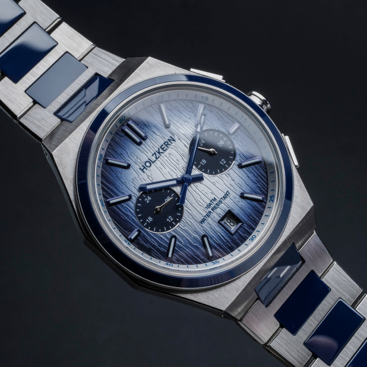 "Oceanswell" watch with a sleek ceramic and silver design, featuring a textured blue dial and metal bracelet.