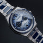 "Oceanswell" watch with a sleek ceramic and silver design, featuring a textured blue dial and metal bracelet.