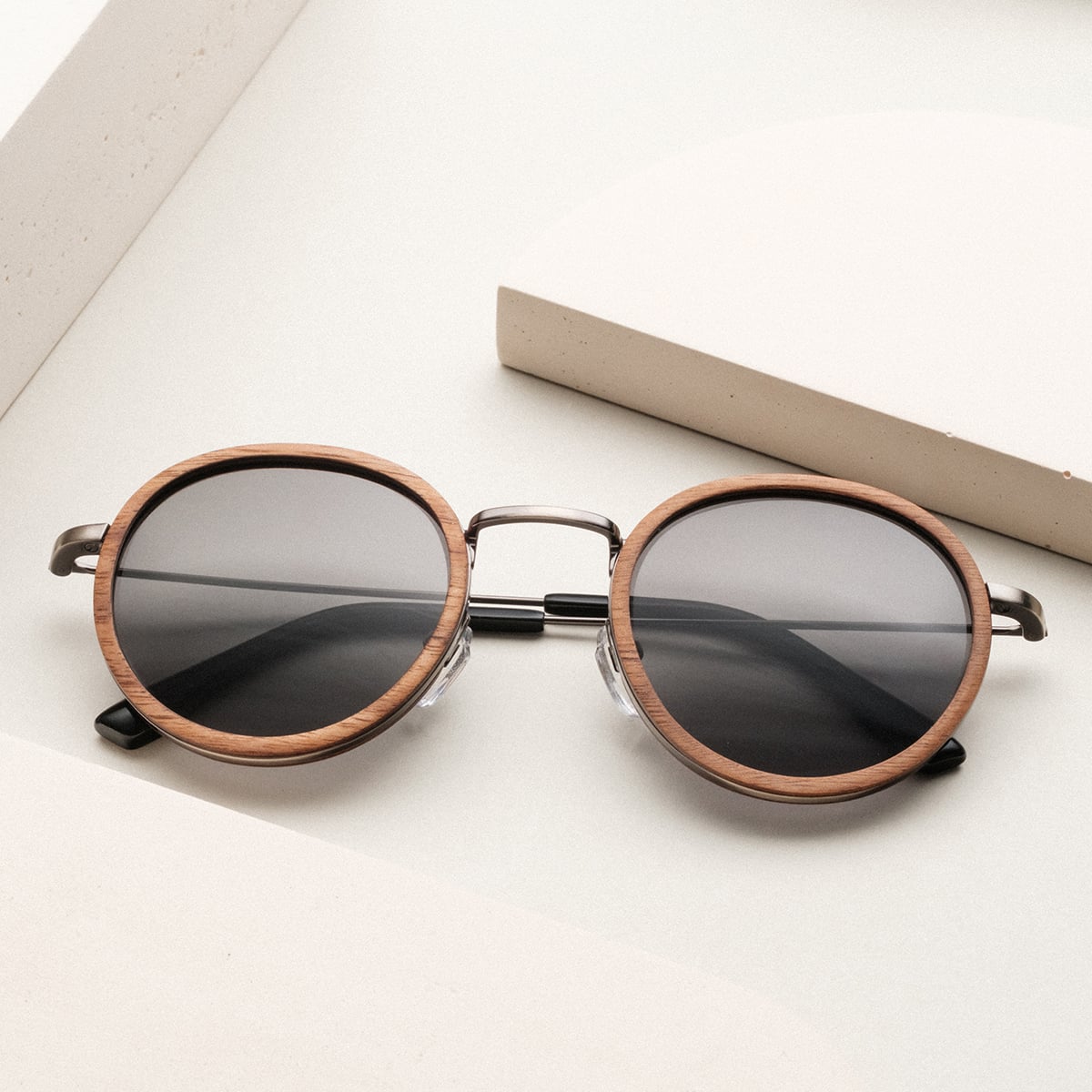 "The Radiant M" sunglasses feature a walnut and antique silver design with round lenses and a stylish frame.