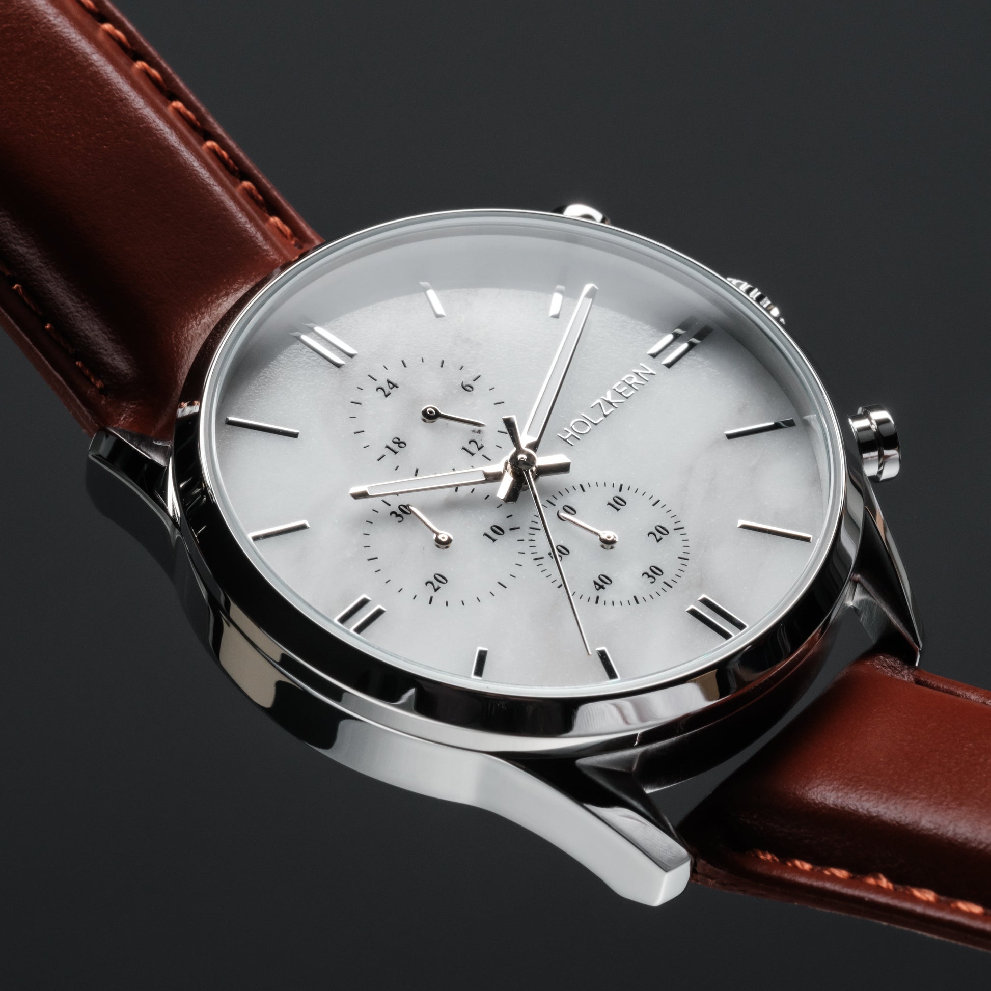 "Melodical", a marble and silver wristwatch, featuring a sleek design with a brown leather strap.