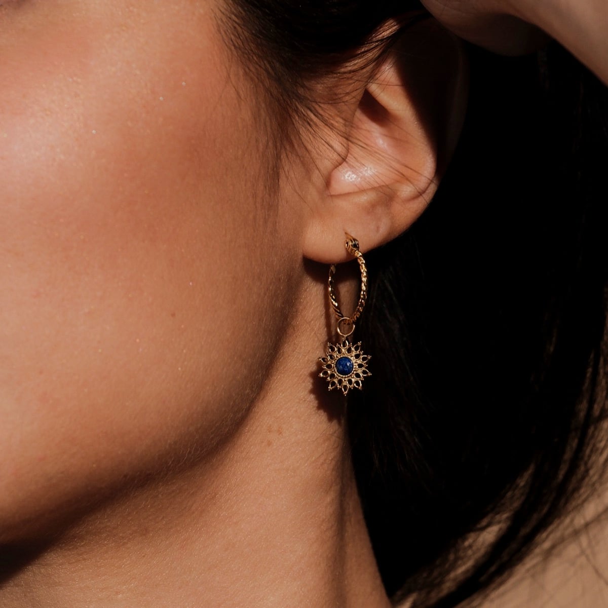Elegant "Suncatcher Earrings" earrings featuring a sunburst design in lapis lazuli and gold tones.
