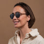 "The Achiever" sunglasses, featuring a chic walnut and copper design, worn by a woman with a stylish look.