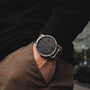 "Odaiba" watch with a sleek black dial and silver casing, worn with casual attire for a modern look.