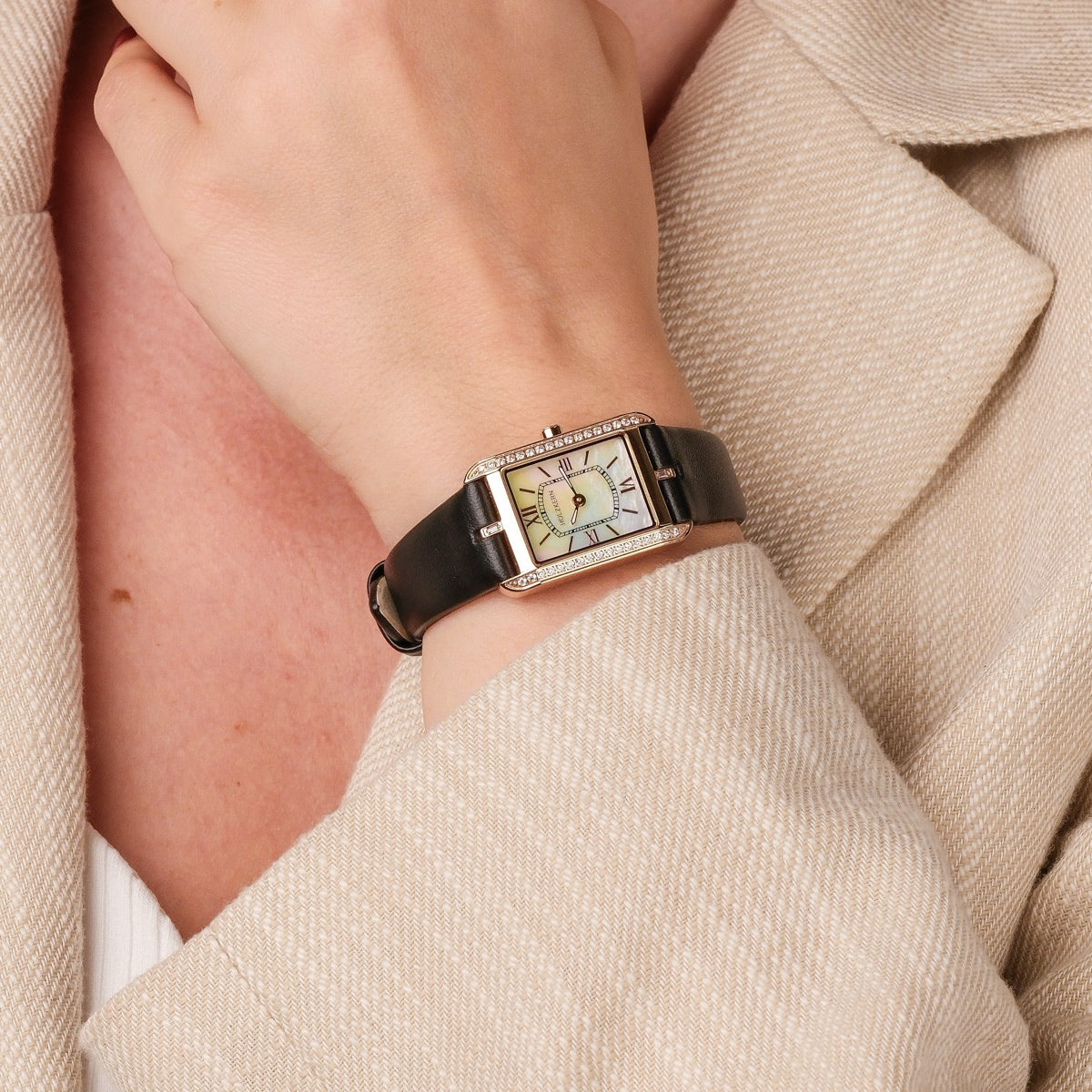 "Memoire", a stylish wristwatch with nacre face and black strap, worn elegantly on a wrist.