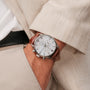 "Melodical" watch featuring a marble dial with silver accents and a brown leather strap, worn on the wrist.