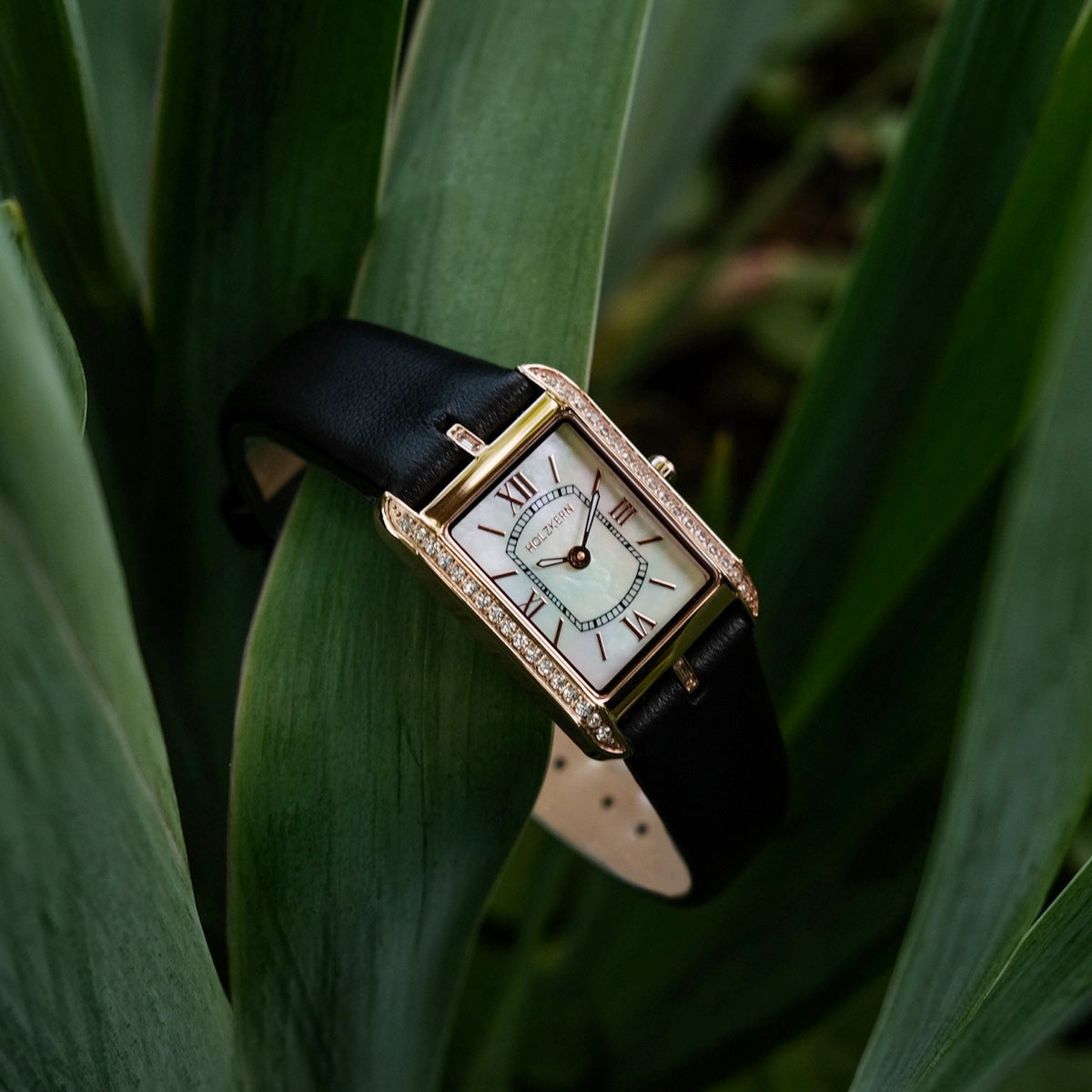 "Memoire" watch featuring a nacre face and black strap, elegantly designed with a rectangular dial and gold accents.