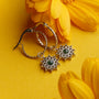 Suncatcher earrings, elegant earrings with a marble and silver design, surrounded by vibrant yellow flowers.