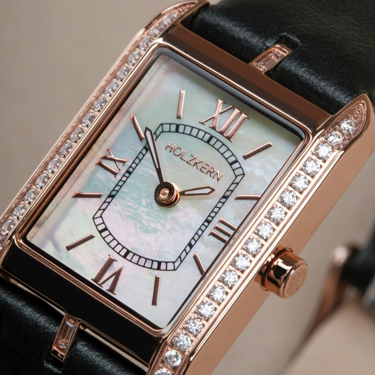 "Memoire", elegant watch with nacre face and black strap, featuring rose gold accents and sparkling stones.