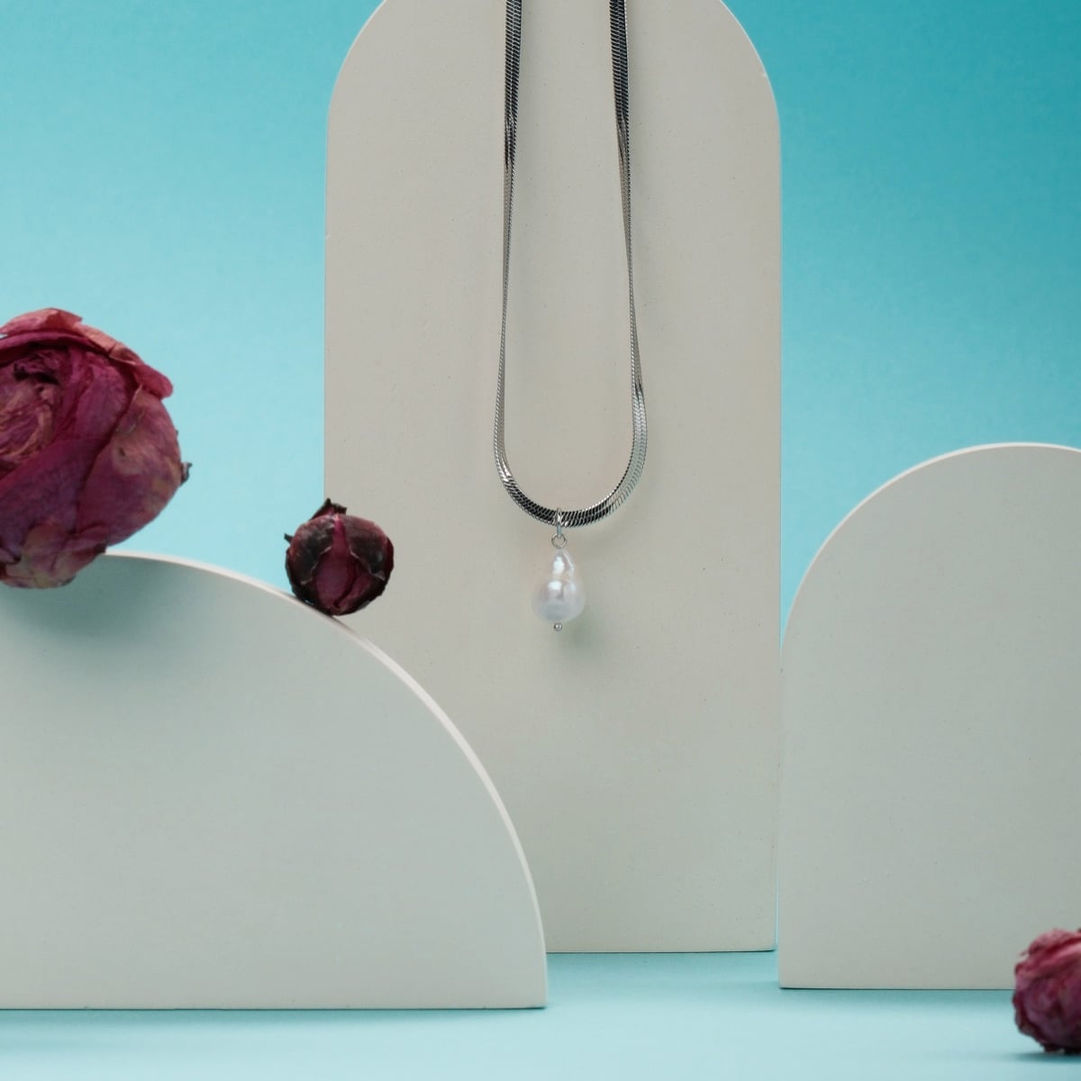 "Summersweet Necklace": An elegant silver necklace featuring a baroque pearl, showcased in a minimalist style with floral accents.