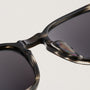 "The Comedian" sunglasses with a Leadwood frame and Khaki Dust lenses, showcasing a sleek and modern design style.