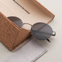 "The Adventurous" sunglasses feature a sleek walnut and dark gray design, nestled in an eco-friendly cork case.