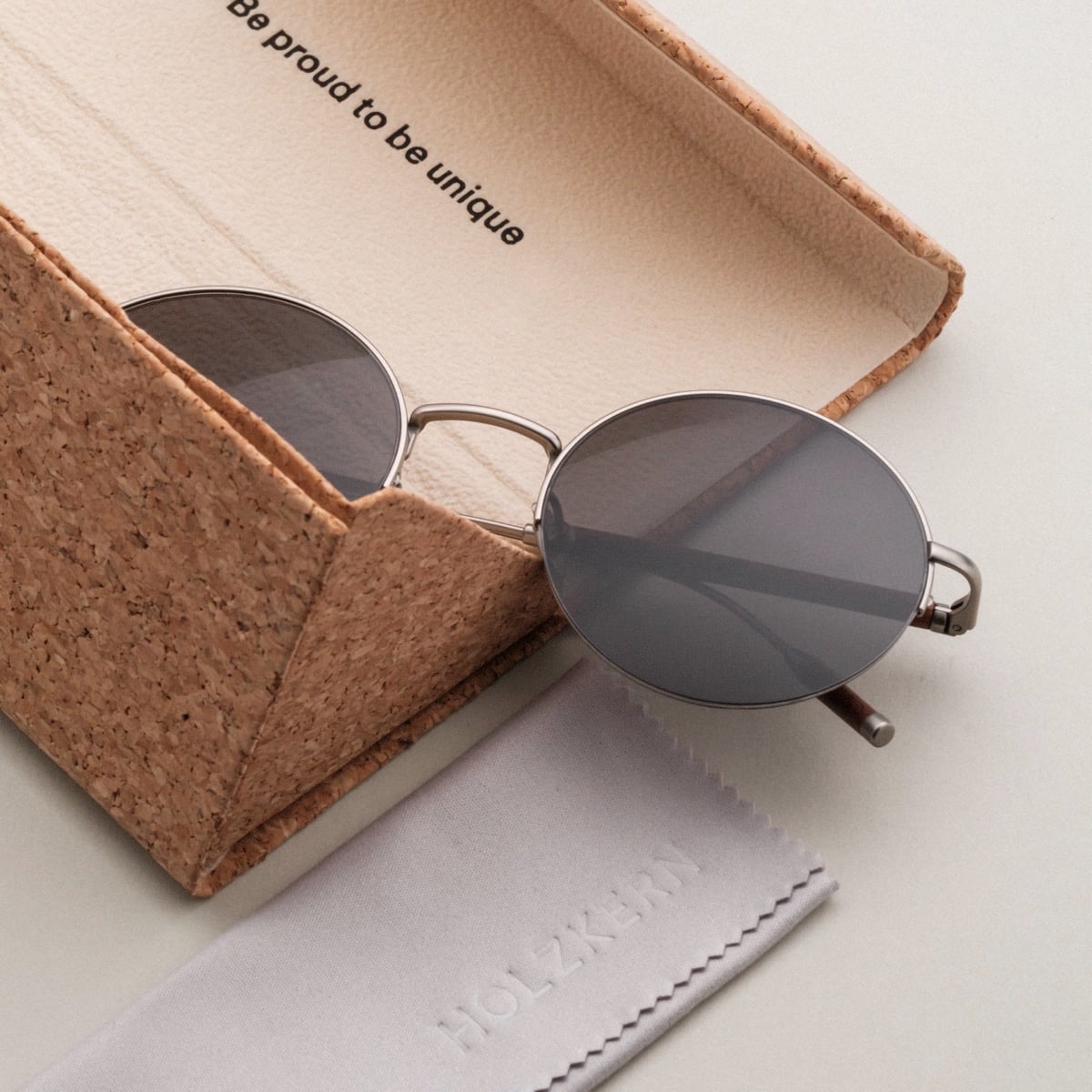 "The Adventurous" sunglasses feature a sleek walnut and dark gray design, nestled in an eco-friendly cork case.