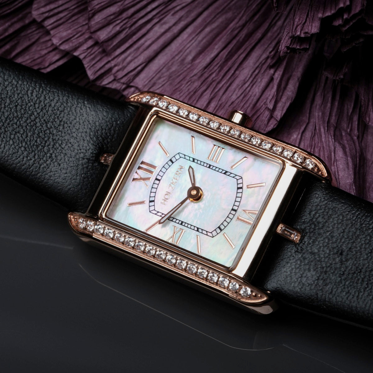 "Memoire" watch featuring a nacre face, black leather strap, and crystal accents.
