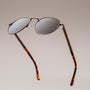 "The Achiever" sunglasses with walnut and copper accents, featuring a sleek and modern round-frame style.