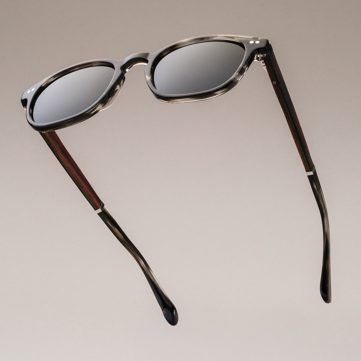 "The Comedian" sunglasses with a sleek Leadwood frame and Khaki Dust accents, offering a stylish, modern design.