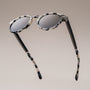 "The Hyped" sunglasses in Leadwood/White Havana, featuring a modern, stylish design with round lenses.