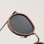"The Wanderer" sunglasses featuring a walnut and bronze frame with a sleek design.