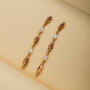"Summersweet Earrings I": Elegant pearl and gold earrings with a delicate, elongated design.