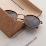 "The Radiant M" sunglasses in walnut and antique silver, featuring a sleek, modern design with a cork case.