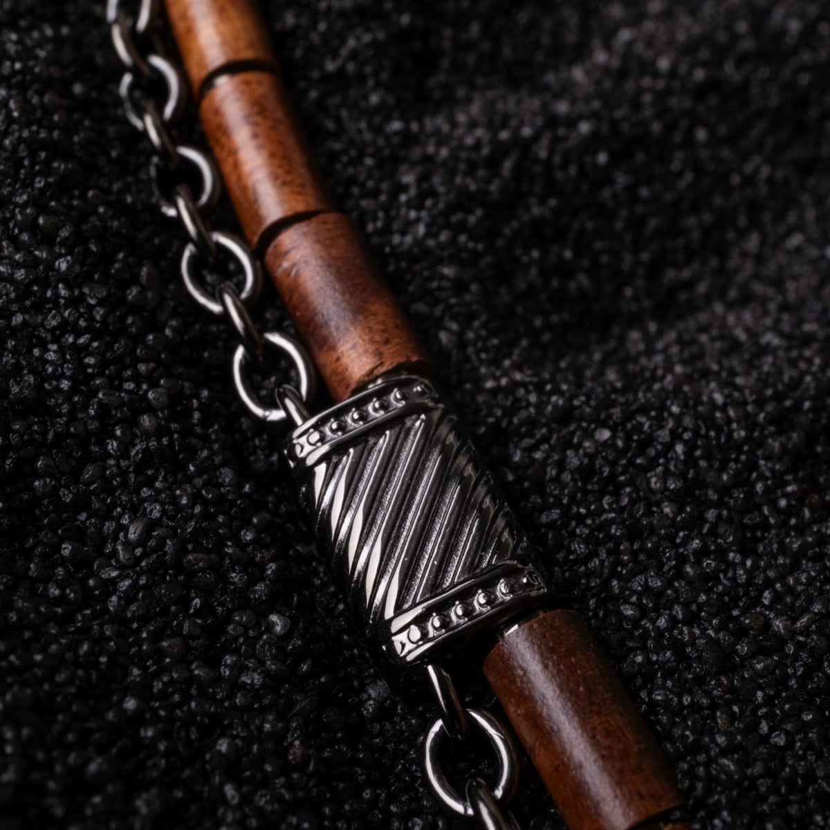 "Supersonic" necklace combines koa wood and gray metal, featuring a sleek, textured design.