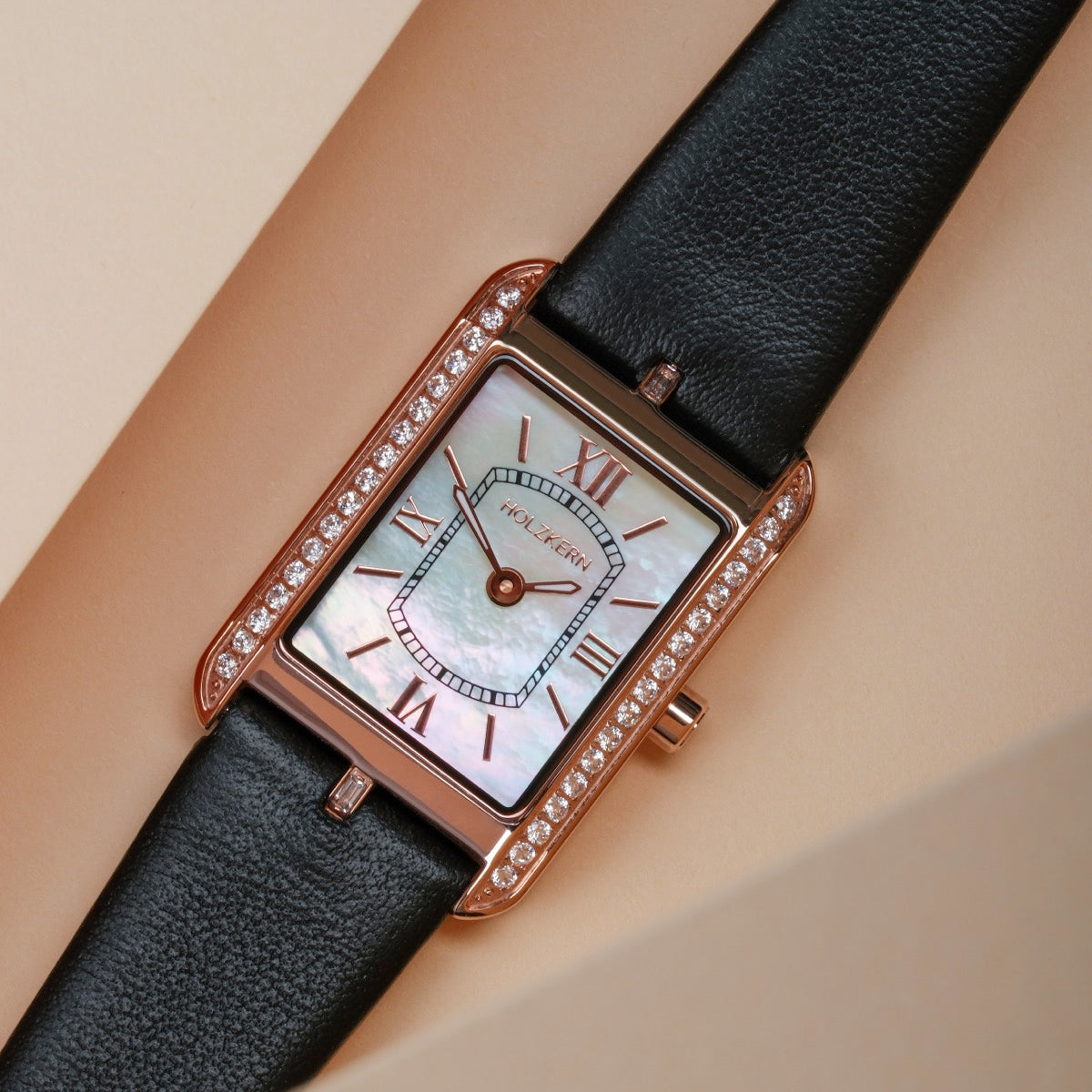 "Memoire" watch featuring a nacre face, black leather strap, and elegant rose-gold accents.