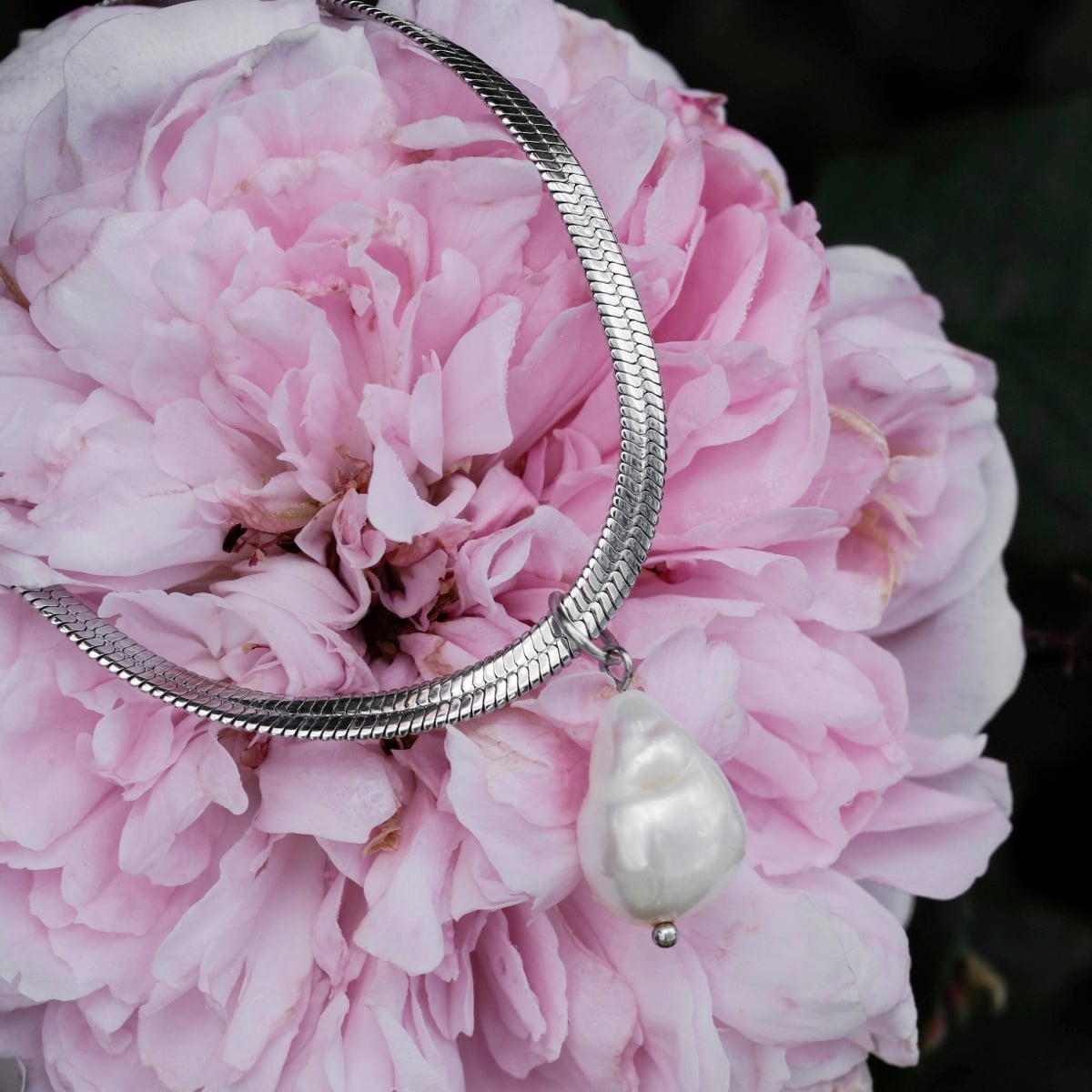 "Summersweet Necklace" necklace featuring a baroque pearl on a silver chain, styled against soft pink petals for an elegant look.