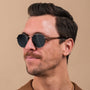 "The Achiever" sunglasses featuring a stylish walnut and copper design worn by a person against a neutral background.